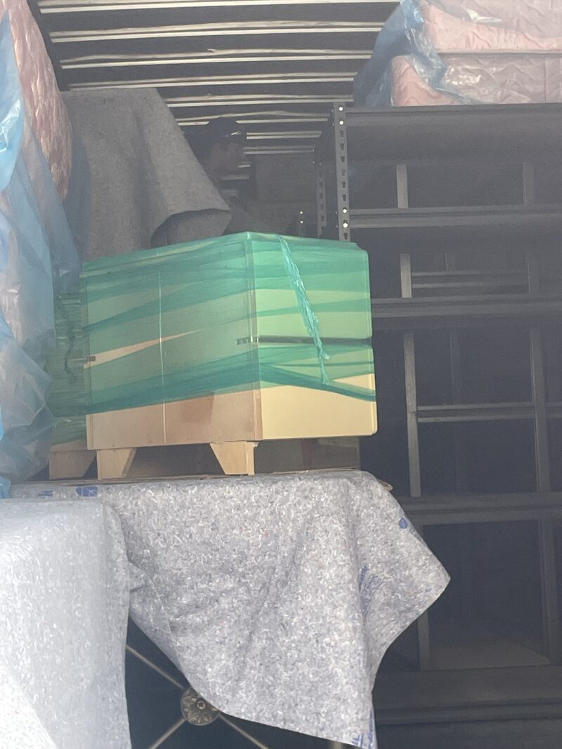 A shrink-wrapped stack of household goods strapped down on a pallet inside the truck